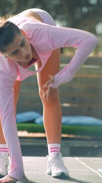 Woman performs warmup stretches in park at sunrise with vibrant attire
