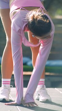 Woman performs warmup stretches in park at sunrise with vibrant attire