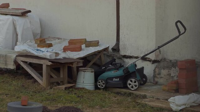 Abandoned garden scene. Silent overgrown yard with forgotten gardening essentials and mossy metal surfaces