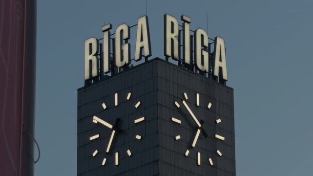 Brightly lit Riga clock tower captured during dusk showcasing architectural elegance and subtle cloud movements