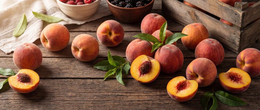 Fresh peaches and leaves on rustic wooden table