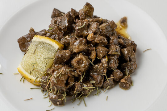 Traditional Italian lamb offal coratella cooked with rosemary and lemon served on white plate isolated on white background.