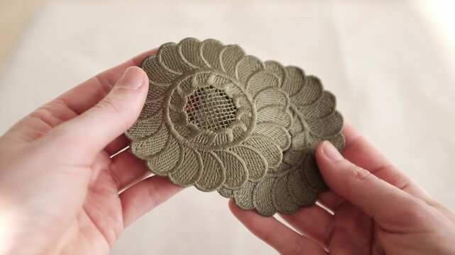 Close-up of hands holding and inspecting floral light green embroidered lace trim with a floral pattern. The video showcases the intricate stitching, scalloped edges, perfect for fashion design