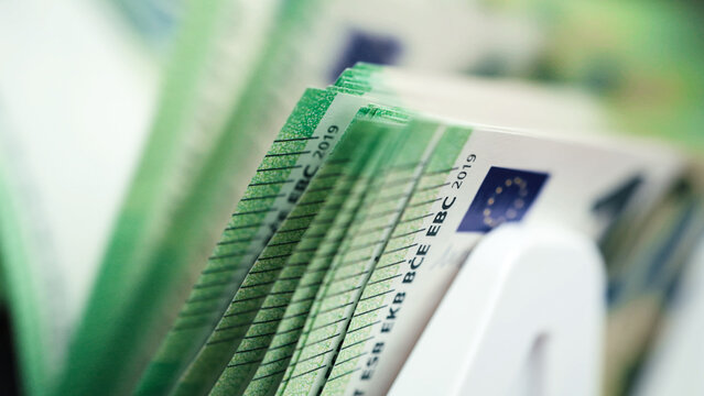 Money counting machine processing stacks of Euro banknotes with detailed currency design visible, showcasing the precision of cash handling technology in a financial setting