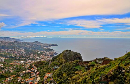 Panoramic View of a Coastal Town: An expansive vista showcasing a charming town nestled along a rugged coastline, with the vast blue ocean meeting the horizon under a dramatic sky.
