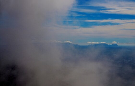 A dramatic view from the cliffs of Cabo Girao, Madeira, showing dense clouds drifting over the vast Atlantic Ocean horizon.