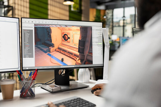 Game developer, works on video game, designing futuristic adventure in space. Black programmer uses modeling tools, animation software and programming commands for a virtual world.
