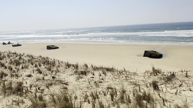 Forward moving view from the top of Cap Ferret dune revealing five German World War II blockhouses that have slid onto the beach following accelerated coastal erosion during recent winter storms
