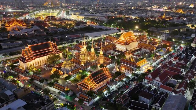 Bangkok, Thailand: Aerial night view of Wat Pho Thai Buddhist temple complex (Temple of the Reclining Buddha) in heart of Thai capital city, Grand Palace on horizon - landscape drone panorama