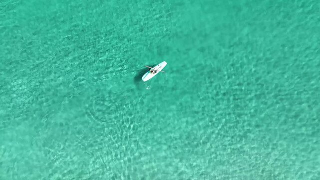Aerial View of Person Relaxing on Stand-Up Paddleboard in Crystal Clear Turquoise Ocean Water