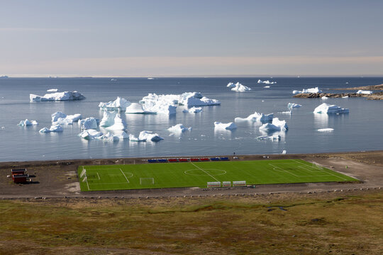 Elevated view of the arctic football field on Disko Island in Greenland with floating icebergs in the background
