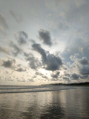 Obraz premium Beautiful tropical beach landscape with dramatic cloudy sky at sunset, calm waves and hills background