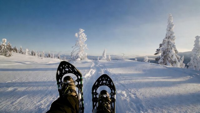 Person wearing snowshoes resting on snowy tundra trail