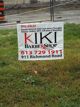 Ottawa, Ontario, Canada-July 23, 2025: A lawn sign for "Kiki Barber Shop" at 911 Richmond Road advertises senior haircut sales and discounts in Ottawa.
