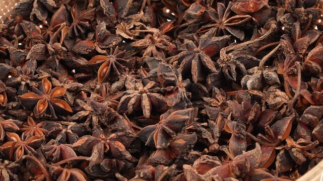 Cinematic slow motion of dried star anise spices dropping onto a pile. Dynamic organic herb footage for Asian culinary and traditional medicine.