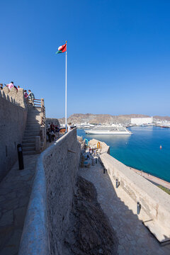 Muscat, Oman &ndash; December 28, 2025: View from Mutrah Fort overlooking Muscat harbor with a large cruise ship anchored in the turquoise waters of the Gulf of Oman. The scene captures historic defensive w