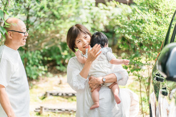 Naklejka premium Senior couple holding their grandchild (returning home, first grandchild, visiting family, parents' home)