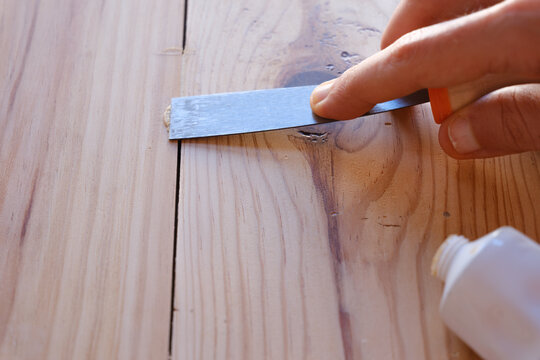 Hand filling pinewood with spatula for wood repair