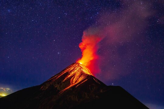 Fuego Volcano erupting at night in Guatemala with glowing lava and starry sky, dramatic volcanic landscape
