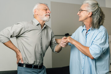 Fototapeta premium Elderly man suffering back pain supported by wife at home