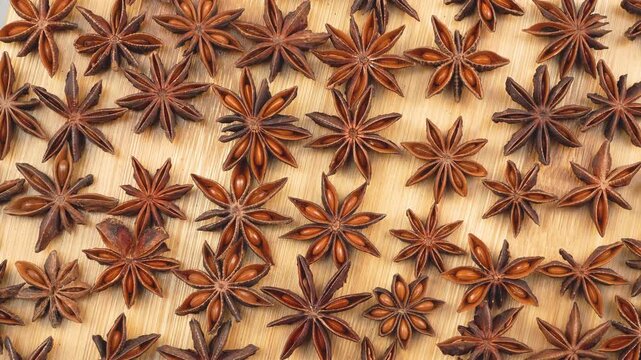 Wide top-down view of scattered dried star anise spices on a wooden background. This abundant organic herb pattern is perfect for Asian culinary and traditional medicine concepts.