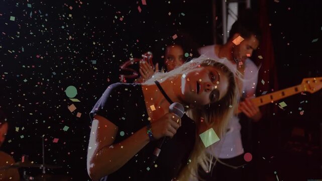 Vertical video: Camera pulling back, lead singer in shorts, crop top, singing mic, confetti falling