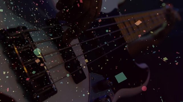 Vertical video: Plucking strings, hands in dark top fretting white bass on stage as confetti rising