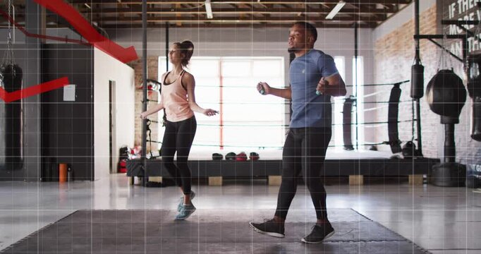 Vertical video: Entering pair jumping ropes for cardio in studio, tank top blue tee, red graphs