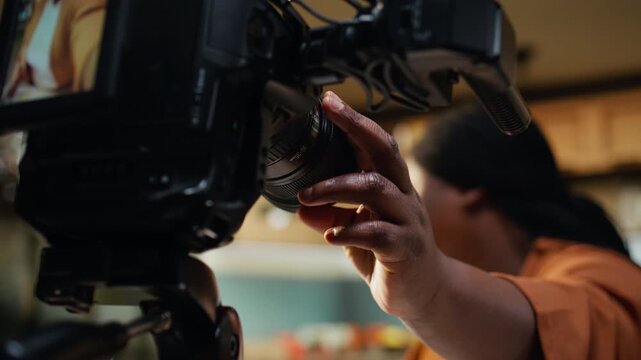Close up, african american woman, fine tuning settings, fixing camera on tripod, vlog filming preparations, behind the scenes footage. Vlogger preparing lighting for smooth recipe video.