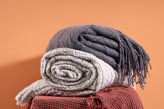 Chair with stack of soft blankets on orange background
