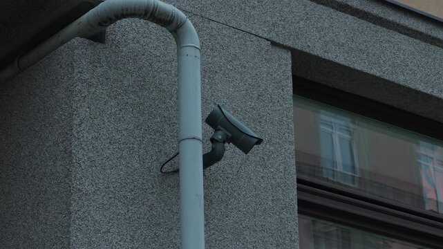 Security device positioned on structure displaying live footage with gray finish and reflective glass