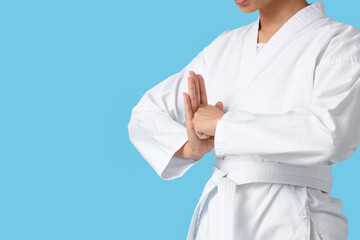Young woman with white belt practicing karate on blue background © Pixel-Shot
