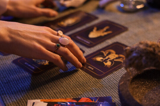 Fortune teller's hands with tarot cards on table, closeup