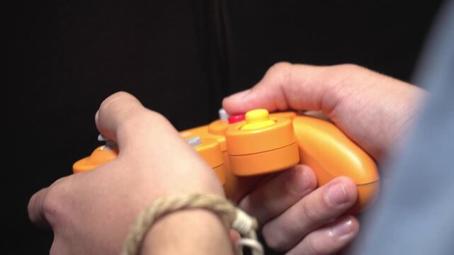 Close up of player holding retro controller while playing classic style video game