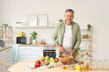 Fototapeta premium Mature man making apple cider at table in kitchen