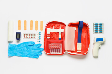 Fototapeta premium First aid kit with pills, infrared thermometer and medical patches on white background