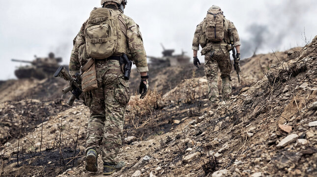 Armed soldiers in camouflage uniforms advance up a desolate, burned hill.