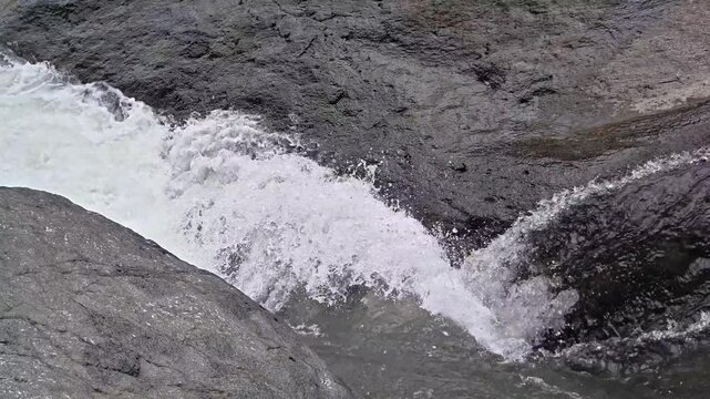 A natural river with a strong current that bury itself among the large rocks around it.