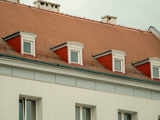Obraz premium Red-tiled roof with dormer windows above white walls