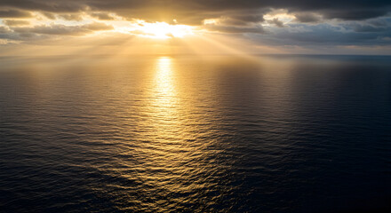 Fototapeta premium Golden Sunset Over the Ocean with Rays of Light Illuminating the Water Surface and Dramatic Clouds in the Evening Sky