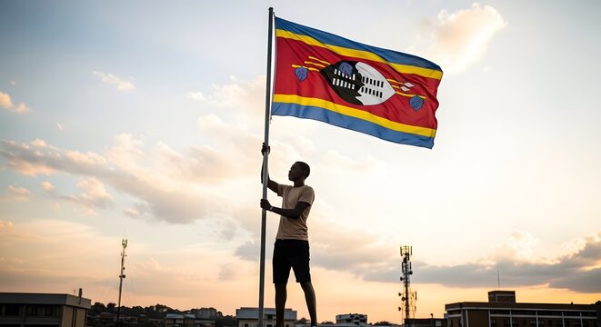A person holds the vibrant national flag of Eswatini high against a dramatic sunset sky, symbolizing national pride and freedom.