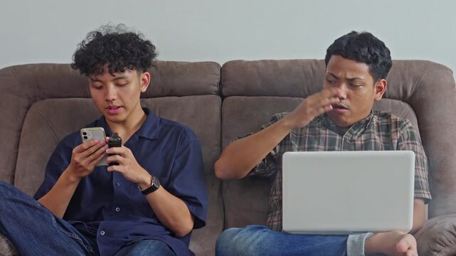 Man asking friend to stop vaping indoors due to secondhand smoke while using laptop