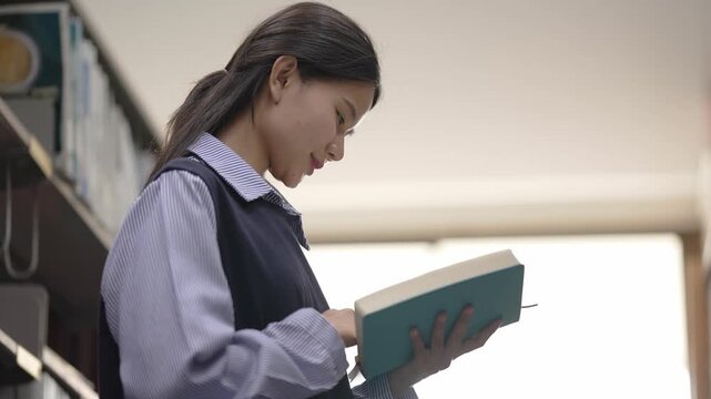 Young Asian Woman University Student Reading Books Alone in Library