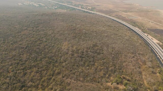 Aerial view of highway running along river and green hills. Transportation, infrastructure, travel and logistics concept