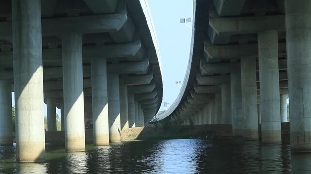 A tall concrete bridge over a river in the city with blue sky and surrounding buildings