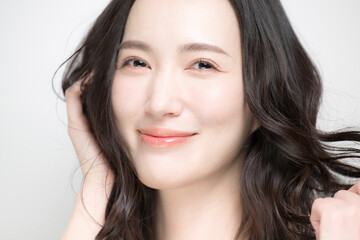 Fototapeta premium 黒髪のパーマのロングヘア、ヘアケア美容ビューティー、カメラ目線の美しいアジア人(日本人)女性イメージ トリートメントや髪の毛のお手入れなどクローズアップ