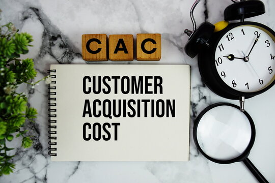 CAC Customer Acquisition Cost text with alarm clock and magnifying glass on marble background