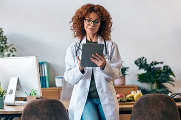 Nutritionist woman working with digital tablet while posing at camera in the nutritionist consultation