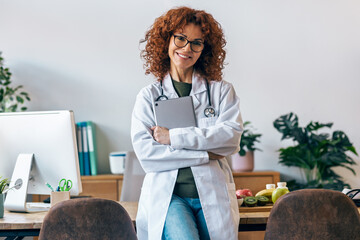 Shot of nutritionist woman working with digital tablet while posing at camera in the nutritionist consultation
