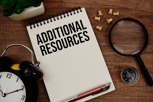 Additional Resources text written on notepad with alarm clock, compass and magnifying glass flat lay on wooden background